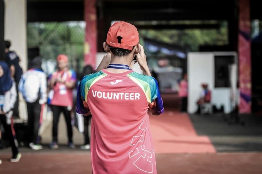 A volunteer in a bright shirt helps at a community event.